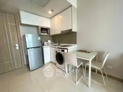 Modern kitchen with sleek appliances and compact dining area in a stylish apartment.