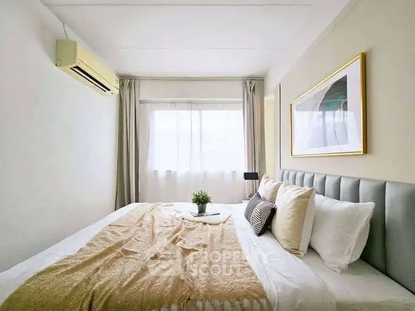 Cozy bedroom with elegant decor and natural light, featuring a plush bed and stylish artwork.
