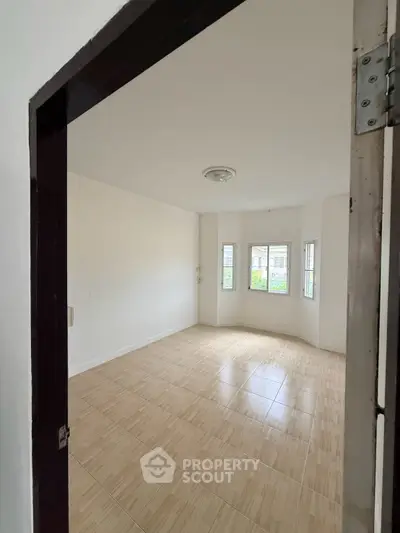 Spacious empty room with large windows and wooden flooring, perfect for customization.