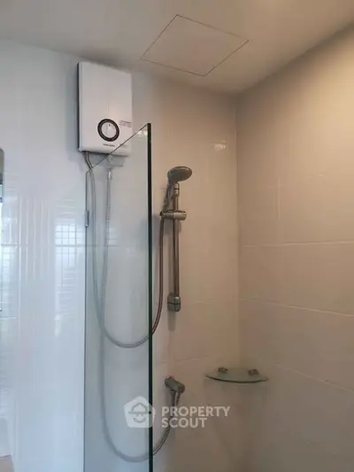 Modern bathroom with sleek shower and water heater in a contemporary home.