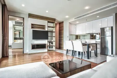 Modern open-plan living room with sleek kitchen and dining area, featuring contemporary furniture and stylish decor.