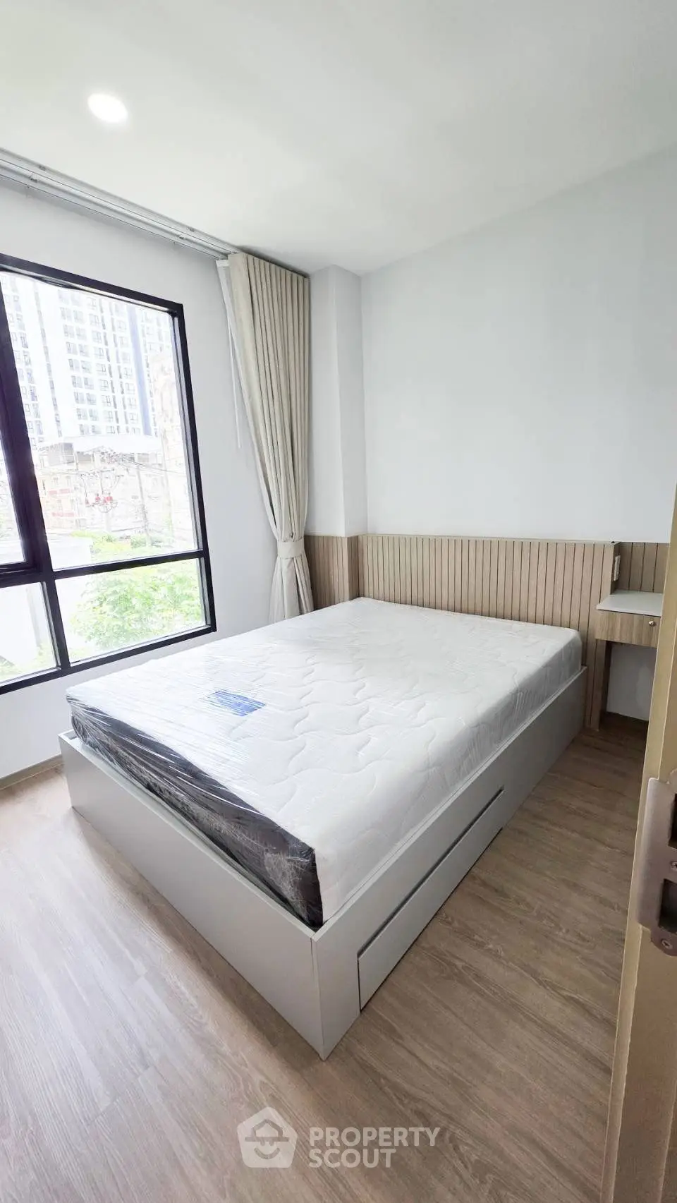 Modern bedroom with large window and minimalist design in urban apartment.