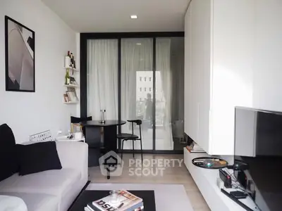 Modern living room with sleek furniture and large window offering natural light.