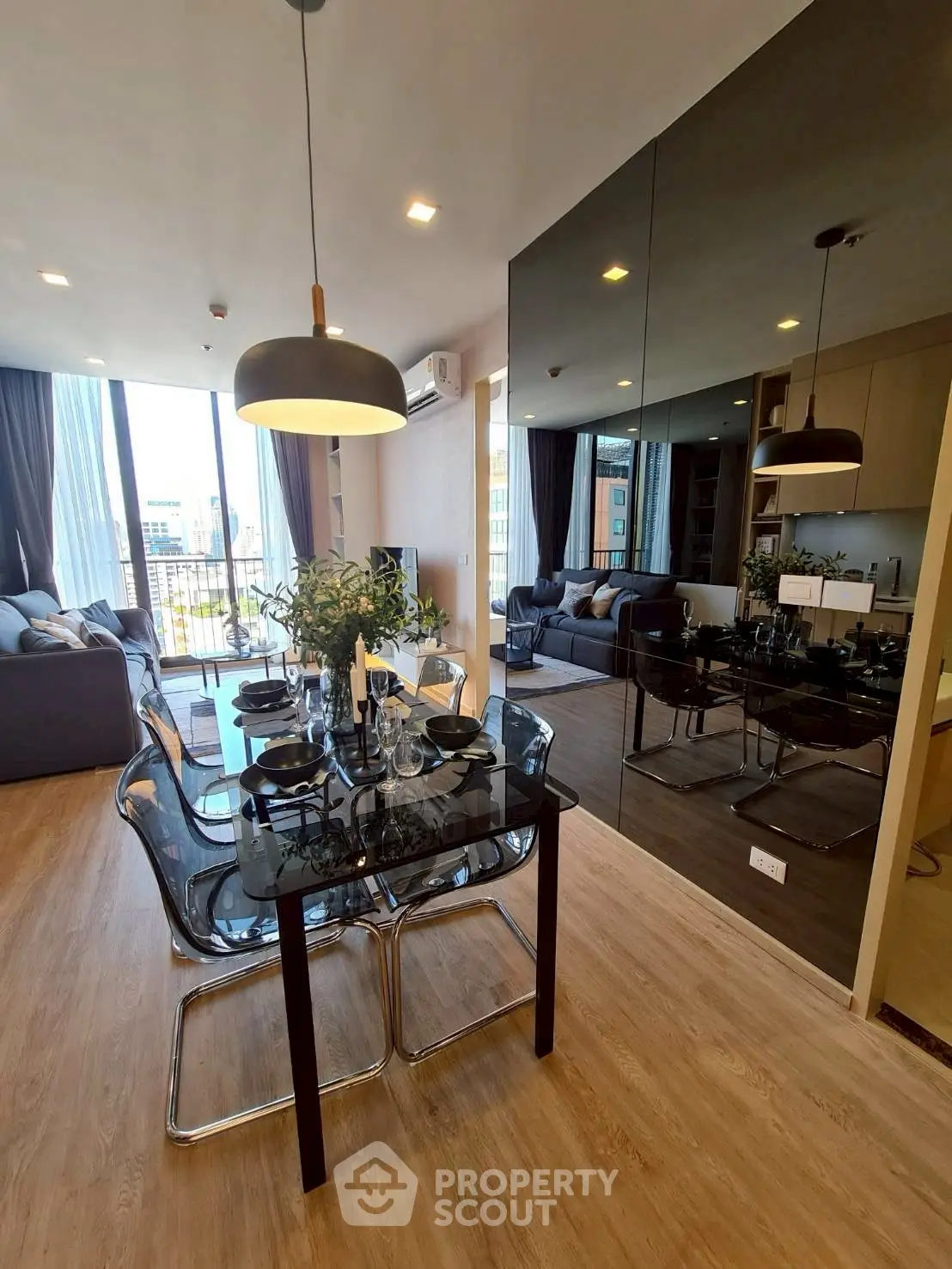 Modern dining area with elegant glass table and stylish lighting in open-plan living space