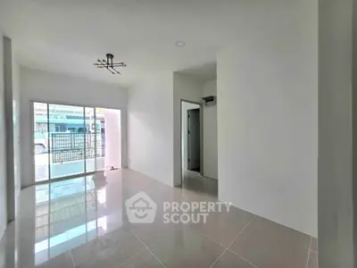 Spacious empty room with large windows and modern lighting in a new home.