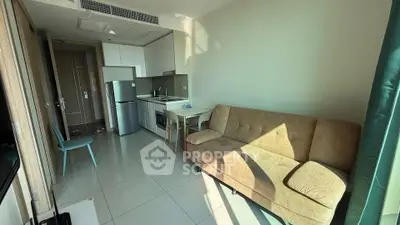 Modern studio apartment with compact kitchen and cozy living area, featuring natural light and contemporary furnishings.