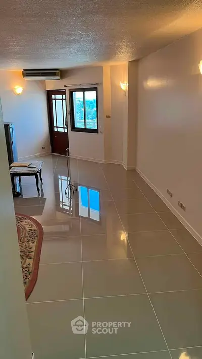Spacious living room with glossy tiled floors and natural light, perfect for modern living.