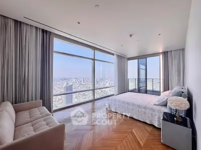 Luxurious bedroom with panoramic city views and elegant decor in high-rise apartment.
