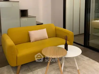 Modern living room with stylish yellow sofa and chic coffee tables on a cozy rug.