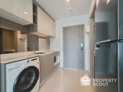 Modern kitchen with sleek appliances and washing machine in compact layout