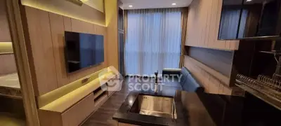 Modern living room with open kitchen and sleek design, featuring a large TV and stylish lighting.