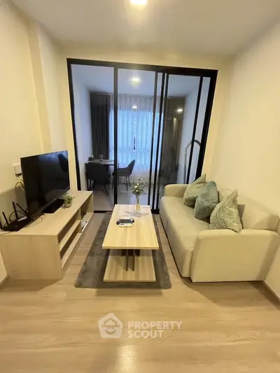 Modern living room with stylish decor and glass partition leading to dining area.