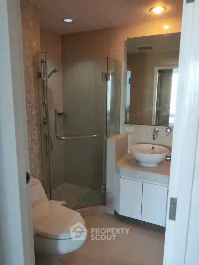 Modern bathroom with glass shower and sleek vanity in a contemporary apartment.