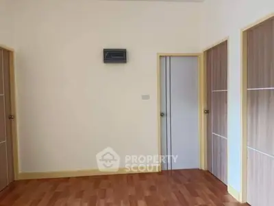 Spacious room with wooden flooring and modern doors, ideal for versatile use.