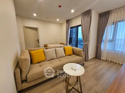 Modern living room with beige sofa and yellow cushions, featuring large windows and wooden flooring.