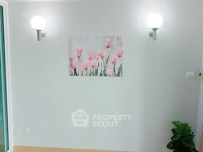 Minimalist interior wall with floral artwork and modern lighting, perfect for a serene living space.
