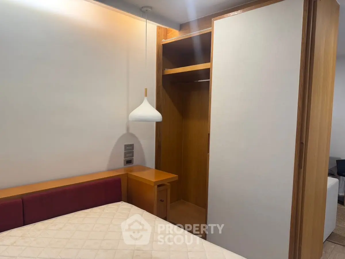 Cozy bedroom with modern wooden wardrobe and pendant light