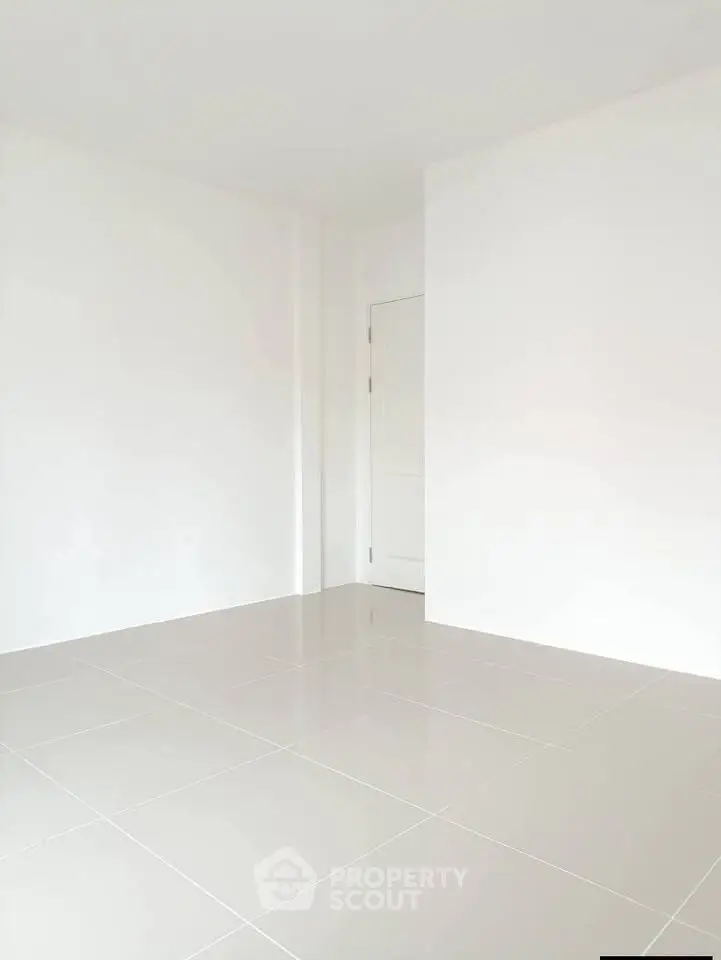 Spacious empty room with glossy tiled floor and white walls, perfect for customization.
