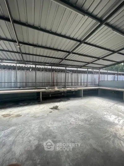 Spacious industrial-style covered area with metal roof and concrete floor, ideal for versatile use.