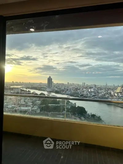 Stunning high-rise view of city skyline and river at sunset from a spacious balcony.