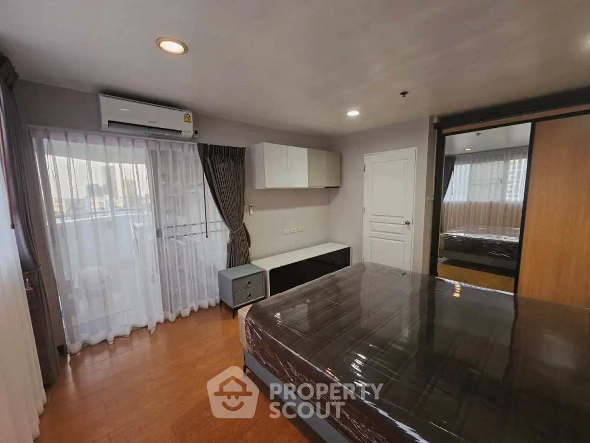 Spacious bedroom with modern furnishings and large windows for natural light.