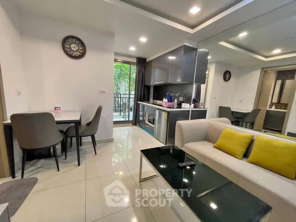 Modern open-plan living room with sleek kitchen and dining area, featuring stylish decor and natural light.