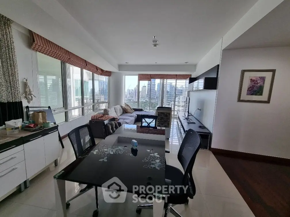 Spacious living room with city view, modern furniture, and natural light in a high-rise apartment.