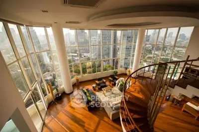 Luxurious penthouse with panoramic city views and elegant spiral staircase in spacious living room.