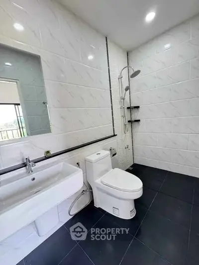 Modern bathroom with sleek fixtures and contemporary design, featuring a spacious shower area.
