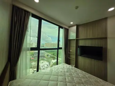 Modern bedroom with large window offering stunning city view, featuring built-in storage and cozy ambiance.