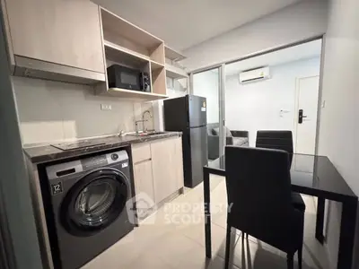Modern kitchen with washing machine and dining area in open layout apartment.