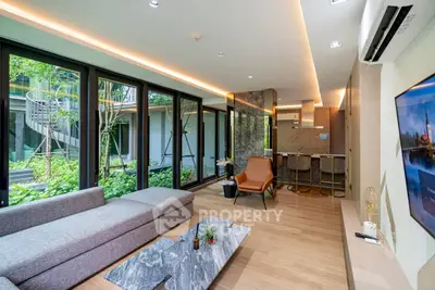 Modern living room with garden view, sleek furniture, and open kitchen layout