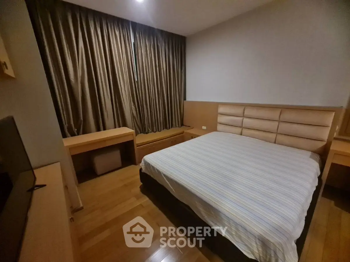 Cozy bedroom with wooden flooring and modern furnishings in a stylish apartment.