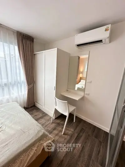 Cozy bedroom with modern furniture and air conditioning, featuring a wardrobe and a study desk by the window.