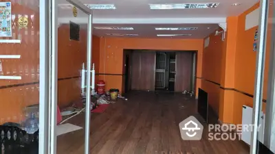 Spacious commercial property with vibrant orange walls and wooden flooring, ideal for retail or office space.