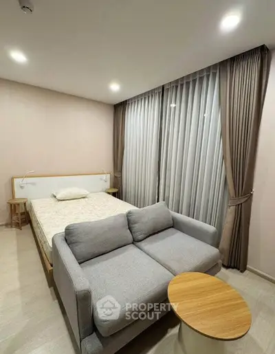 Modern bedroom with cozy sofa and elegant curtains, perfect for relaxation and comfort.