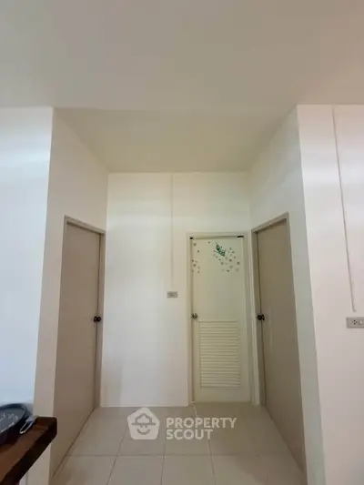 Minimalist hallway with three doors and tiled flooring