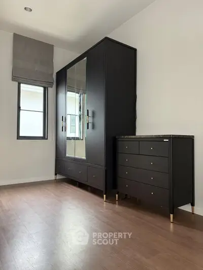 Modern bedroom with sleek black wardrobe and chest of drawers