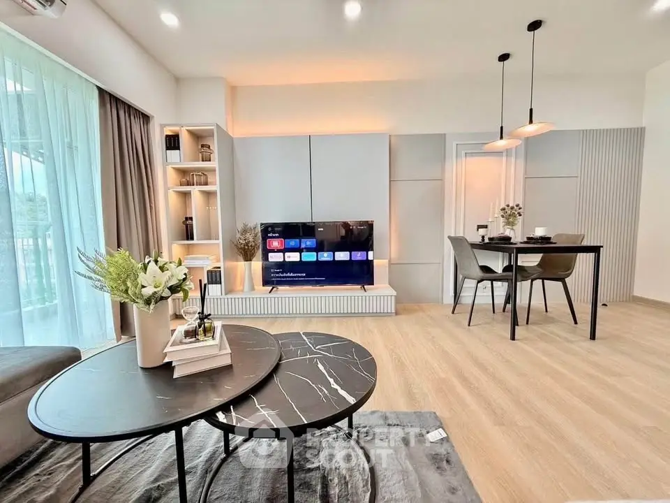 Modern living room with stylish decor and open dining area, featuring a sleek TV setup.