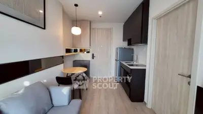 Modern compact living room with kitchenette, featuring sleek design and cozy seating area.