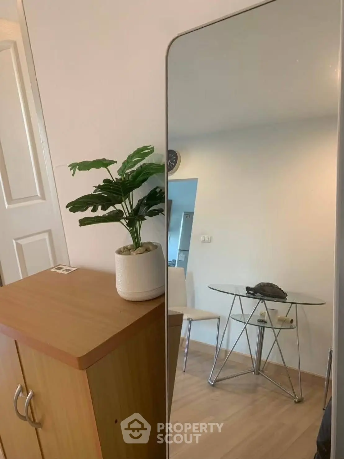 Modern interior with stylish mirror, wooden cabinet, and glass table in a cozy living space.