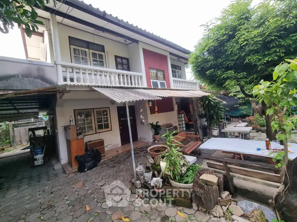 Charming two-story house with spacious outdoor patio and lush greenery, perfect for family gatherings.