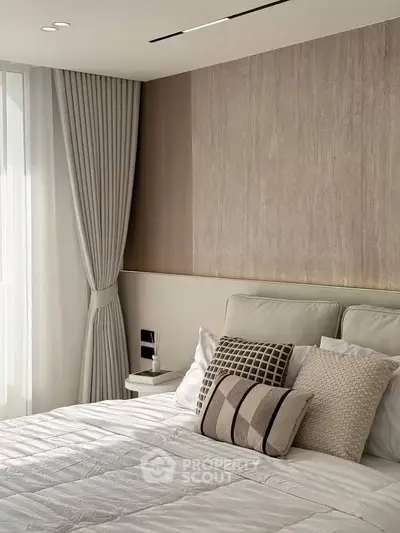 Elegant bedroom with modern decor and soft lighting, featuring plush pillows and stylish curtains.