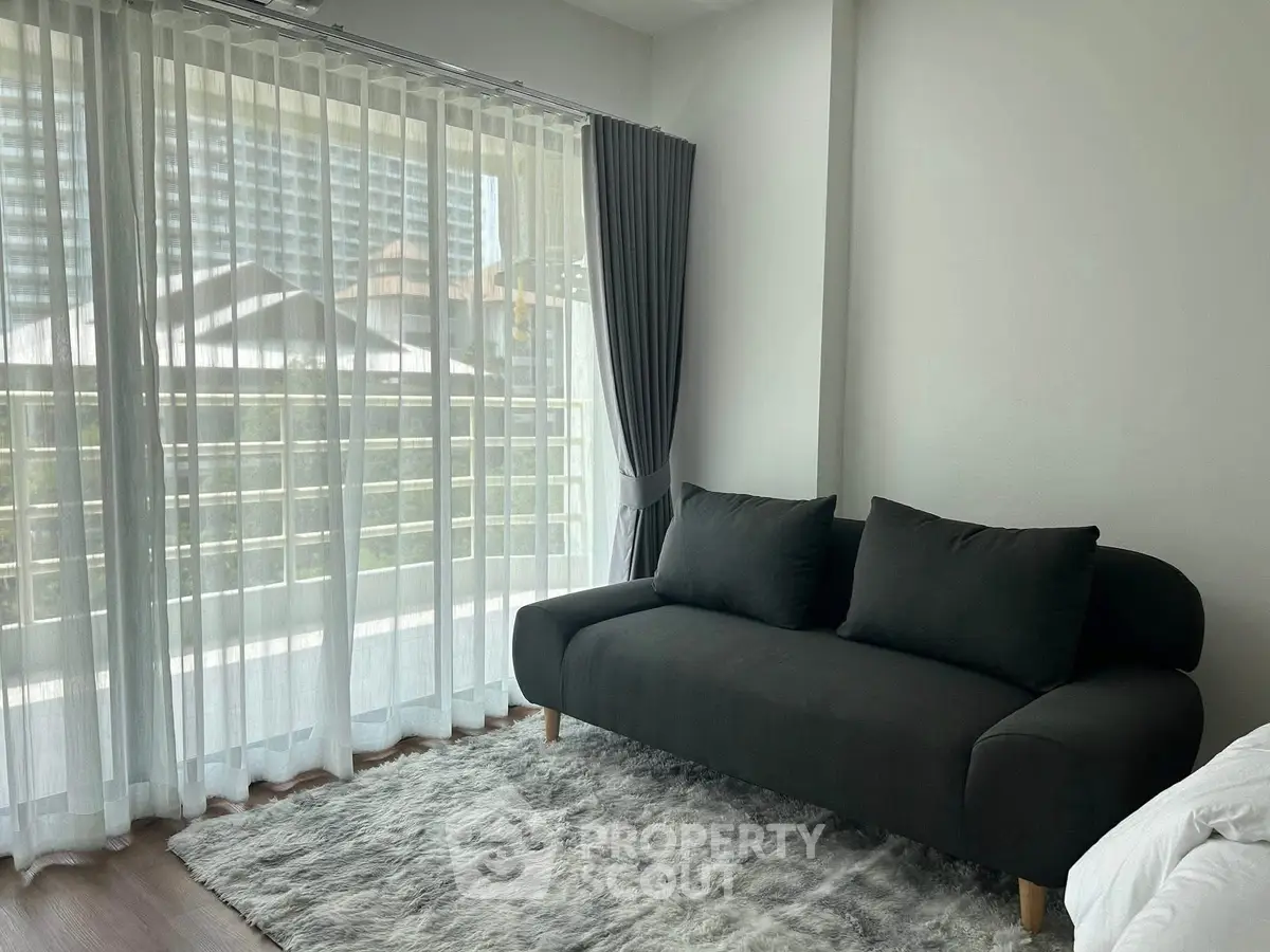 Modern living room with large windows and stylish black sofa, offering a bright and inviting atmosphere.