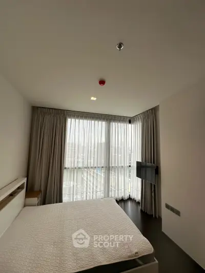 Modern bedroom with large windows and natural light in a stylish apartment.