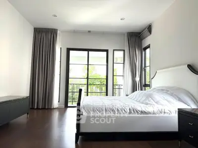Spacious bedroom with large windows and elegant decor, offering a serene view of the outdoors.