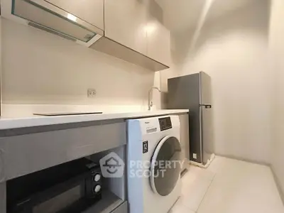 Modern kitchen with sleek appliances including washing machine and fridge, featuring minimalist design.