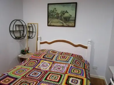 Cozy bedroom with colorful bedding and wall art, perfect for a comfortable living space.