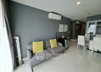 Modern living room with sleek gray sofa and dining area in open layout apartment.