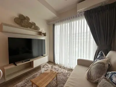 Cozy living room with modern decor, large TV, and natural light through sheer curtains.